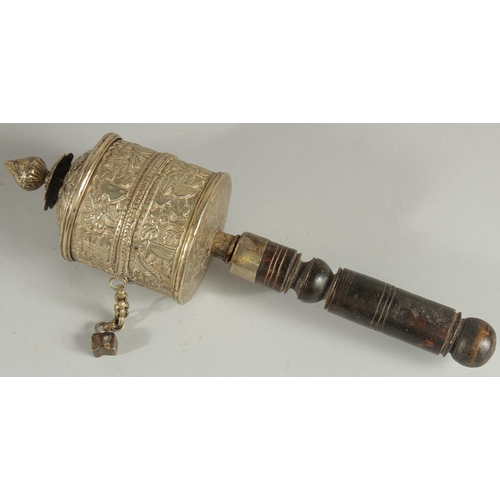 312 - A TIBETAN EMBOSSED SILVER PRAYER WHEEL CONTAINING SCROLL, 27cm long.