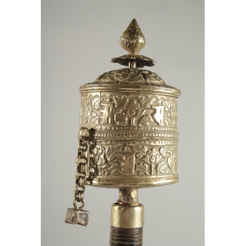 312 - A TIBETAN EMBOSSED SILVER PRAYER WHEEL CONTAINING SCROLL, 27cm long.