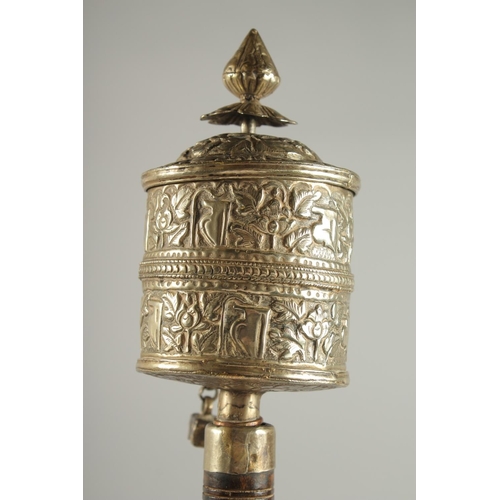 312 - A TIBETAN EMBOSSED SILVER PRAYER WHEEL CONTAINING SCROLL, 27cm long.