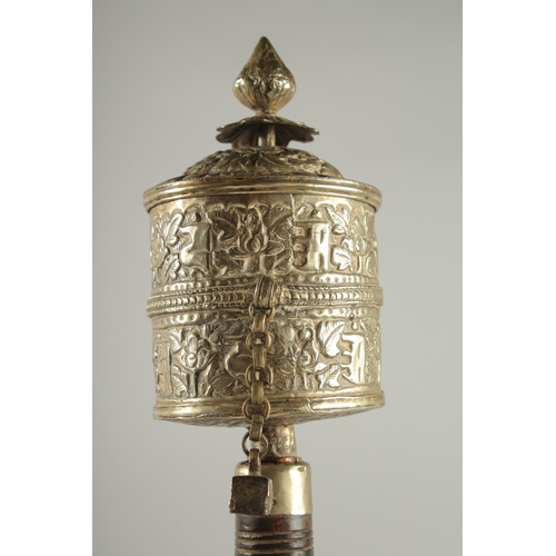 312 - A TIBETAN EMBOSSED SILVER PRAYER WHEEL CONTAINING SCROLL, 27cm long.