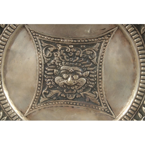 350 - A TIBETAN OR NEPALESE EMBOSSED WHITE METAL DISH, 24cm diameter.