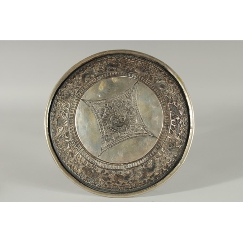 350 - A TIBETAN OR NEPALESE EMBOSSED WHITE METAL DISH, 24cm diameter.