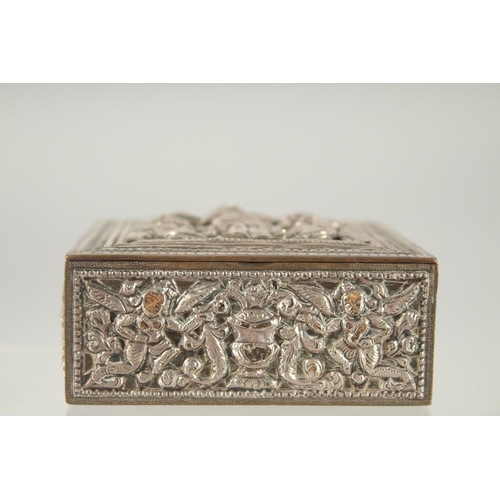 387 - AN INDIAN SILVER OVERLAID SQUARE BOX, with hinged lid and relief decoration, 8cm square.