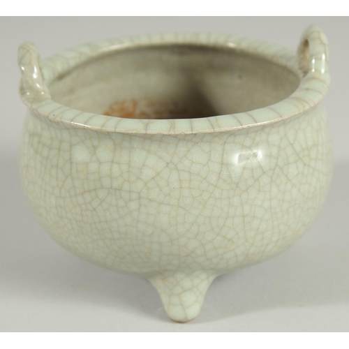 64 - A CHINESE CELADON CRACKLE GLAZE TWIN HANDLE TRIPOD CENSER, 10.5cm diameter.