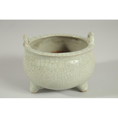 64 - A CHINESE CELADON CRACKLE GLAZE TWIN HANDLE TRIPOD CENSER, 10.5cm diameter.