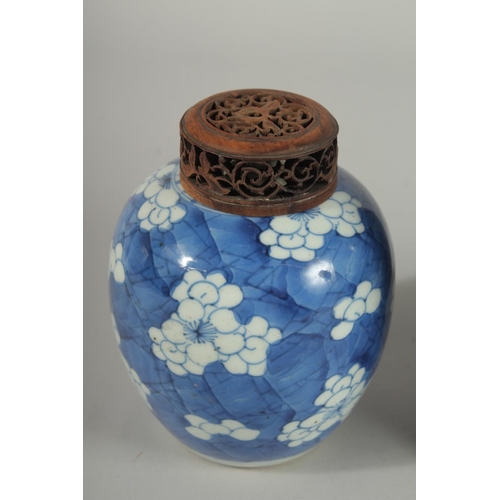 9 - THREE CHINESE BLUE AND WHITE PRUNUS JARS AND COVERS, two with wooden covers and one with wooden stan... 