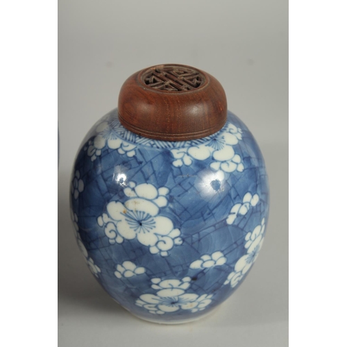 9 - THREE CHINESE BLUE AND WHITE PRUNUS JARS AND COVERS, two with wooden covers and one with wooden stan... 