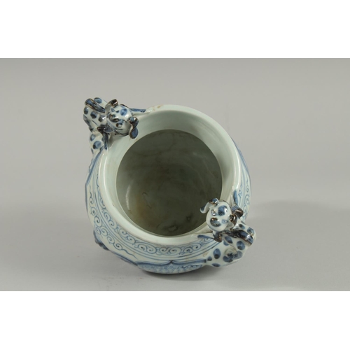 90 - A CHINESE BLUE AND WHITE PORCELAIN TRIPOD CENSER, with moulded dog handles, 20.5cm high.