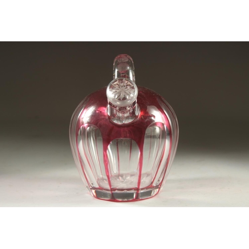 1103 - A SLICE CUT RUBY TINTED GLASS EWER with stopper. 7ins high.