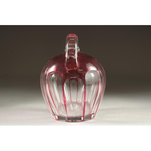 1103 - A SLICE CUT RUBY TINTED GLASS EWER with stopper. 7ins high.