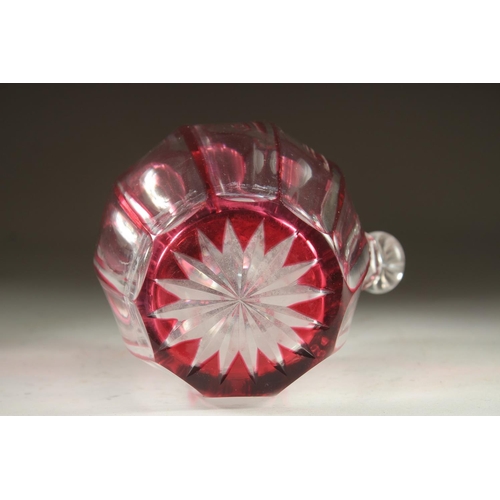 1103 - A SLICE CUT RUBY TINTED GLASS EWER with stopper. 7ins high.