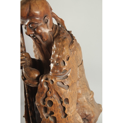 151 - A VERY LARGE AND FINE WOOD CARVING OF SHAO LOU, mounted to a natural tree trunk base, the figure hol... 