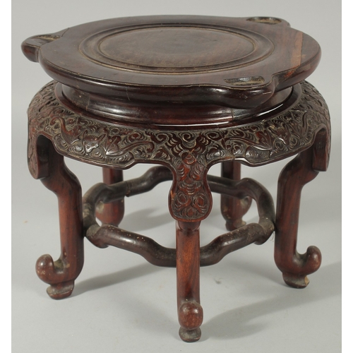 184 - A LARGE CHINESE CARVED HARDWOOD STAND, with circular top, the skirt carved with bat motifs, elevated... 