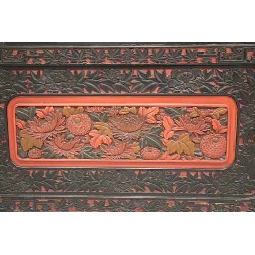 185 - A LARGE 19TH CENTURY CHINESE CARVED BLACK AND RED CINNABAR LACQUER PANEL, depicting two male figures... 