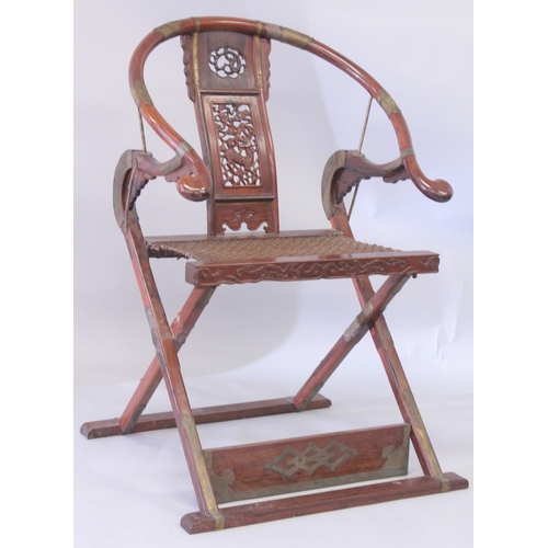 187 - A CHINESE HARDWOOD HORSESHOE-BACK FOLDING CHAIR, with carved and pierced kylin panel and netted seat... 