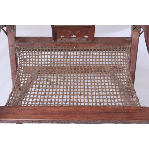 187 - A CHINESE HARDWOOD HORSESHOE-BACK FOLDING CHAIR, with carved and pierced kylin panel and netted seat... 