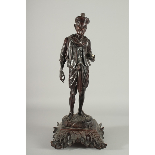 191 - A LARGE INDIAN CARVED HARDWOOD FIGURE, of a man holding a parasol with bone finial, raised and mount... 