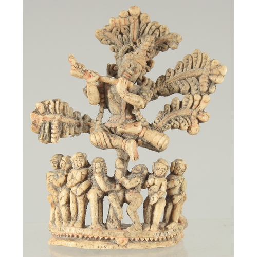 228 - A FINE 17TH-18TH CENTURY SOUTH INDIAN CARVED BONE FLUTING KRISHNA UNDER TREE, 10.5cm high.