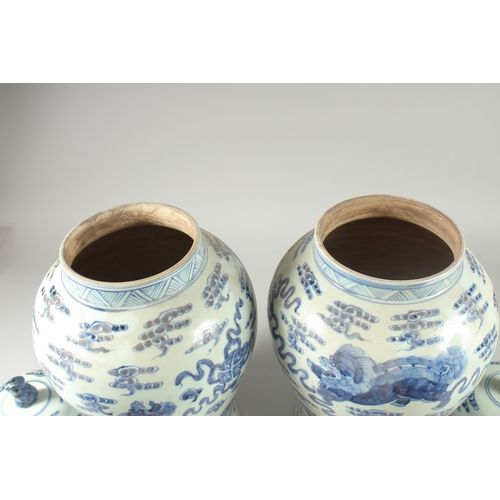 31 - A LARGE PAIR OF CHINESE BLUE AND WHITE PORCELAIN JARS AND COVERS, decorated with foo dogs, 53cm high... 