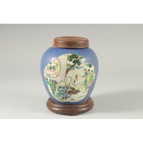 36 - AN EARLY 20TH CENTURY CHINESE BLUE GROUND FAMILLE VERTE PORCELAIN JAR, with wooden cover and stand.