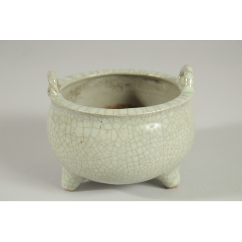 44 - A CHINESE CELADON CRACKLE GLAZE TWIN HANDLE TRIPOD CENSER, 10.5cm diameter.