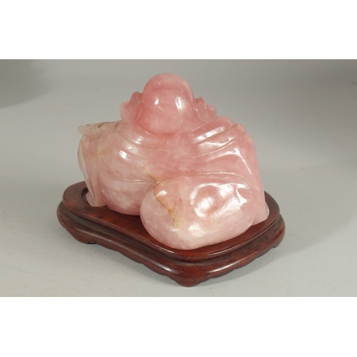 99 - A CHINESE CARVED ROSE QUARTZ BUDDHA on wooden stand, 19cm wide overall.