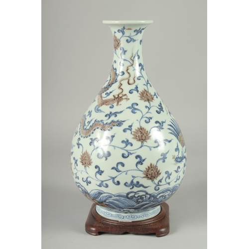 107 - A CHINESE UNDERGLAZE RED, BLUE AND WHITE DRAGON AND PHOENIX YUHUCHUNPING VASE, on a fitted hardwood ... 