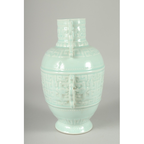 111 - A CHINESE CARVED CELADON GLAZE PORCELAIN VASE, with four pierced handles and carved bands of archaic... 