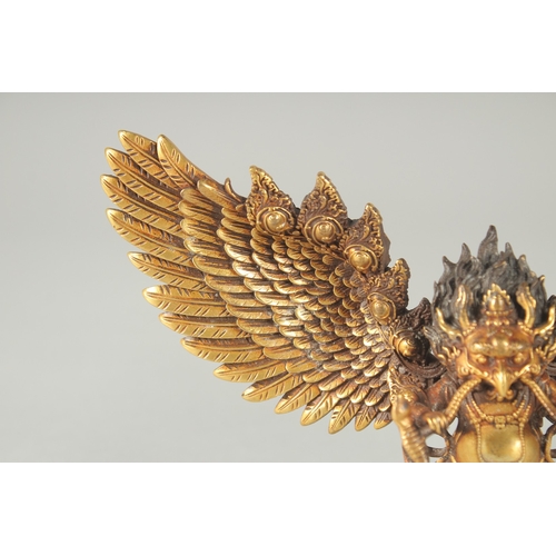 125 - A FINE TIBETAN GILT BRONZE DEITY, with wings outstretched, inscribed to the base, 19cm wide.