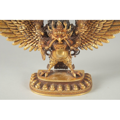 125 - A FINE TIBETAN GILT BRONZE DEITY, with wings outstretched, inscribed to the base, 19cm wide.