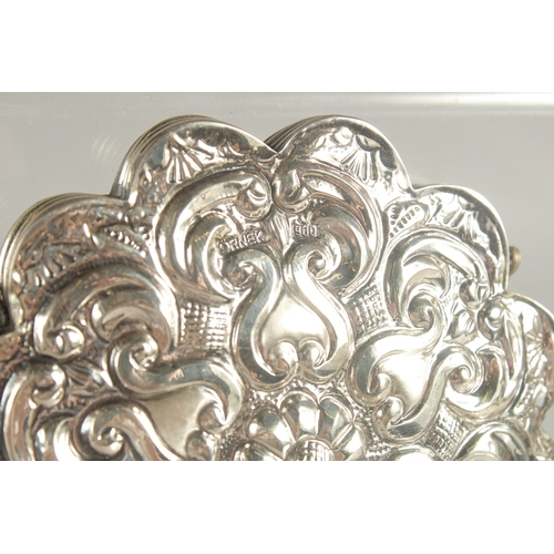 129 - A SMALL EMBOSSED SILVER MIRROR, 10cm wide.