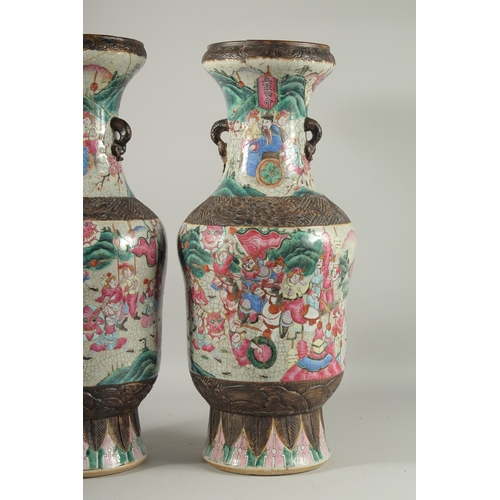 132 - A LARGE PAIR OF CHINESE FAMILLE ROSE PORCELAIN VASES, with moulded twin handles, each painted with a... 