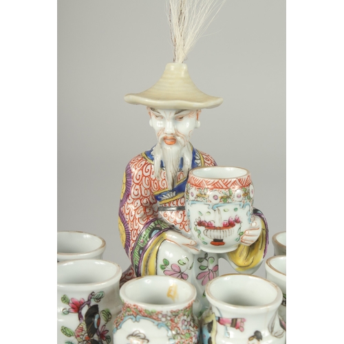 138 - A 19TH CENTURY FAMILLE ROSE PORCELAIN FIGURAL GROUP of a seated vase seller surrounded by six vase-f... 