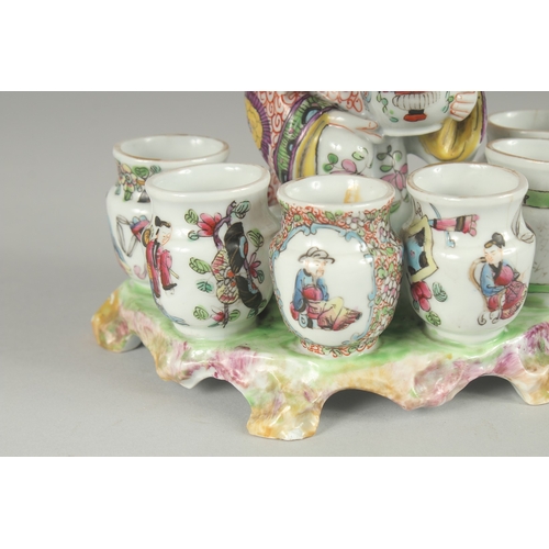 138 - A 19TH CENTURY FAMILLE ROSE PORCELAIN FIGURAL GROUP of a seated vase seller surrounded by six vase-f... 