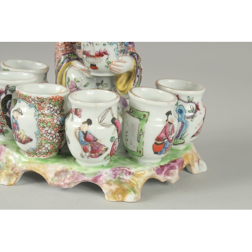 138 - A 19TH CENTURY FAMILLE ROSE PORCELAIN FIGURAL GROUP of a seated vase seller surrounded by six vase-f... 