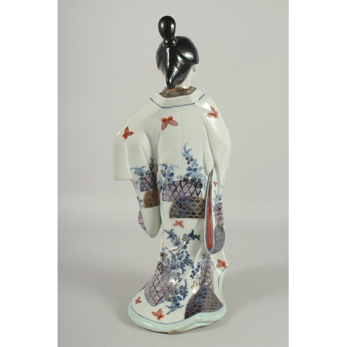 142 - A FINE AND LARGE JAPANESE ARITA PORCELAIN BIJIN, the robe painted with blue and white patterns and r... 