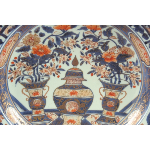 190 - A FINE 18TH CENTURY JAPANESE IMARI PORCELAIN CHARGER, painted with a central lidded jar with vases o... 