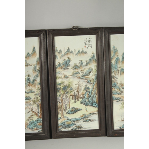 40 - FOUR CHINESE FAMILLE VERTE PORCELAIN PANELS, inset within wooden frames, each depicting mountainous ... 