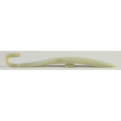 580 - A LONG CARVED JADE BELT HOOK, with dragon head, 25.5cm long.