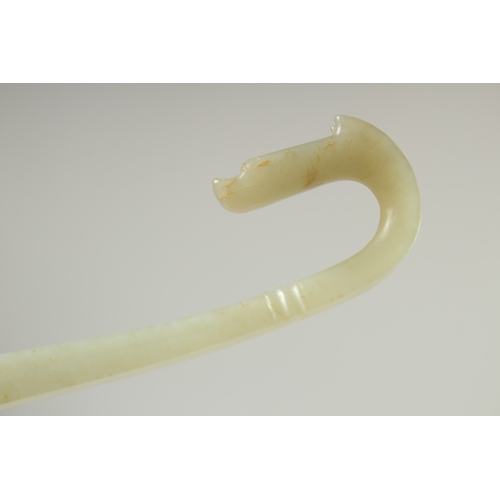 580 - A LONG CARVED JADE BELT HOOK, with dragon head, 25.5cm long.