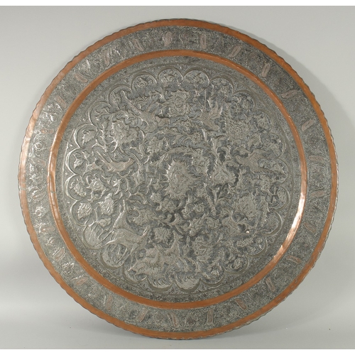 606 - A VERY LARGE ISLAMIC ENGRAVED TINNED COPPER TRAY, with raised engraved decoration depicting animals ... 