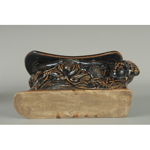 64 - A CHINESE FIGURAL GLAZED POTTERY PILLOW, 25cm long.