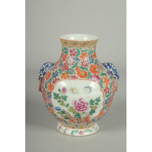 69 - A SMALL CHINESE FAMILLE ROSE PORCELAIN TWIN HANDLE VASE, painted with flora, the base with character... 