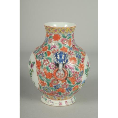 69 - A SMALL CHINESE FAMILLE ROSE PORCELAIN TWIN HANDLE VASE, painted with flora, the base with character... 