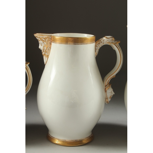 1074 - A GARNITURE OF THREE WHITE PORCELAIN GILDED JUGS with mask spouts.