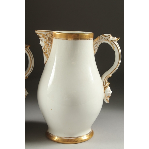 1074 - A GARNITURE OF THREE WHITE PORCELAIN GILDED JUGS with mask spouts.