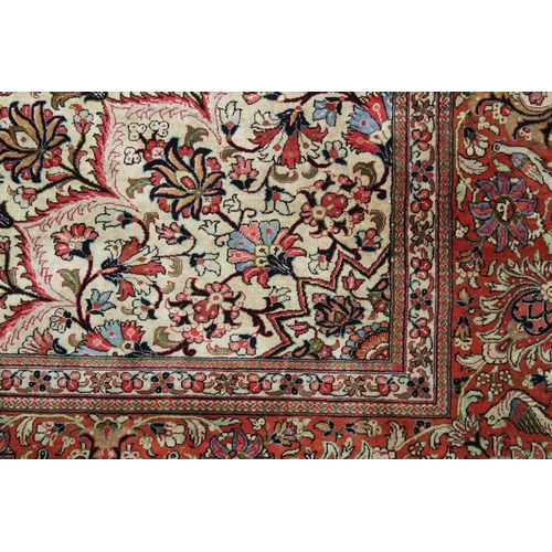 1009 - A GOOD LARGE PERSIAN SILK CARPET cream ground within a red ground border, decorated with floral and ... 