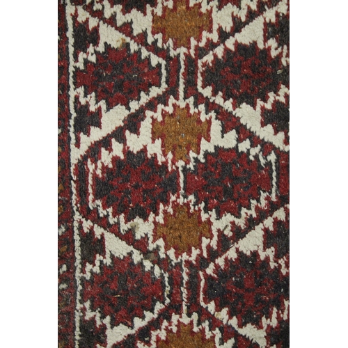 1015 - A SMALL PERSIAN MAT red ground with a geometric design. 2ft x 1ft 4ins.