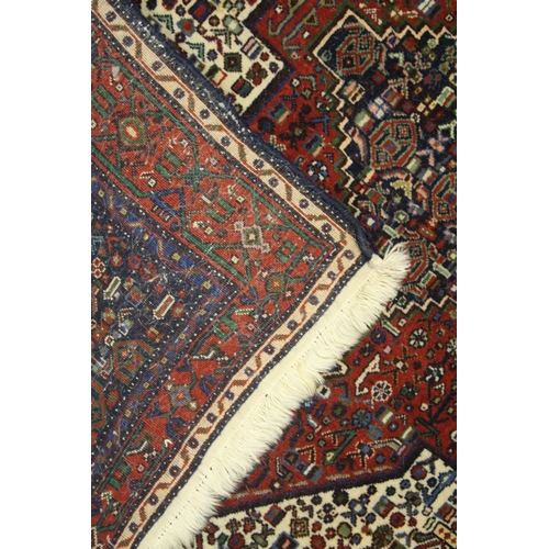 1017 - A PERSIAN WOOL CARPET cream, red and blue ground with all over stylised decoration. 4ft 9ins x 4ft 1... 