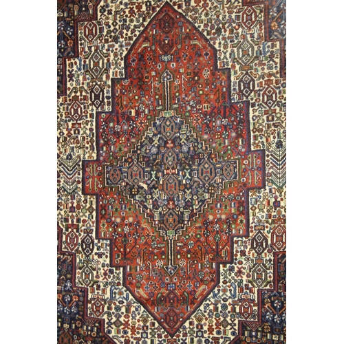 1018 - A PERSIAN WOOL CARPET cream, red and blue ground with all over stylised decoration. 4ft 9ins x 4ft 1... 